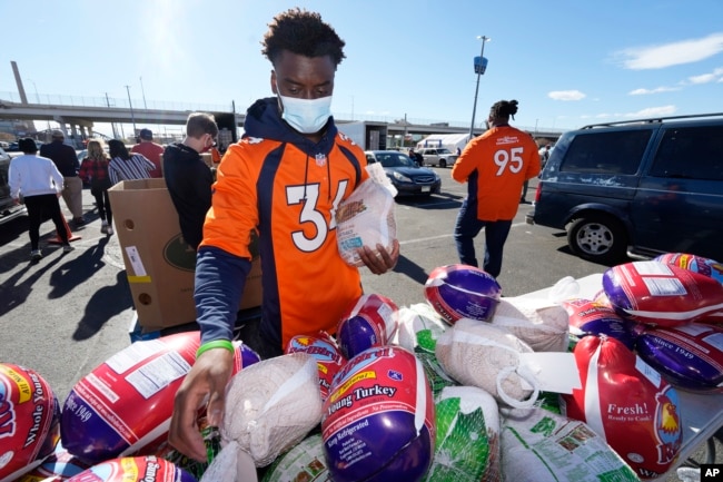 Denver Broncos cornerback Essang Bassey selects frozen turkeys to place in Thanksgiving Day banquet boxes in a vehicle, Nov. 23, 2021, outside Empower Field at Mile High in Denver, Colorado.