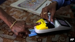 FILE - A woman places her finger on a biometric card reader before buying her quota of subsidized rice from a fair price shop under the Public Distribution System in Rayagada, in the Indian eastern state of Orissa, March 20, 2012.