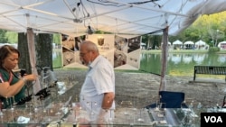 Haydar Serezli, right, speaks to a walk-up customer at his booth at the Festival In the Park in Charlotte, North Carolina, on Sept. 25, 2021. (Salim Fayeq/VOA)