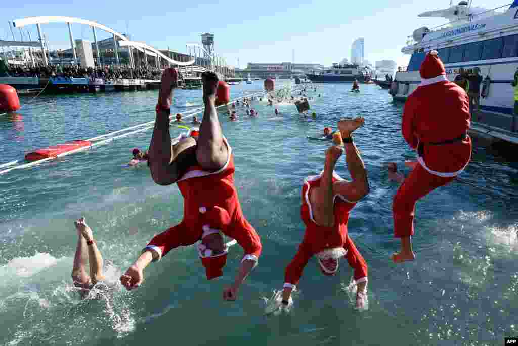 អ្នកចូលរួមស្លៀកឈុត Santa Claus លោតចូលក្នុងទឹកក្នុងការប្រកួតហែលទឹកគ្រឹស្តស្មាស Copa Nadal នៅកំពង់ផែ Port Vell ទីក្រុង Barcelona ប្រទេសអេស្ប៉ាញ។
