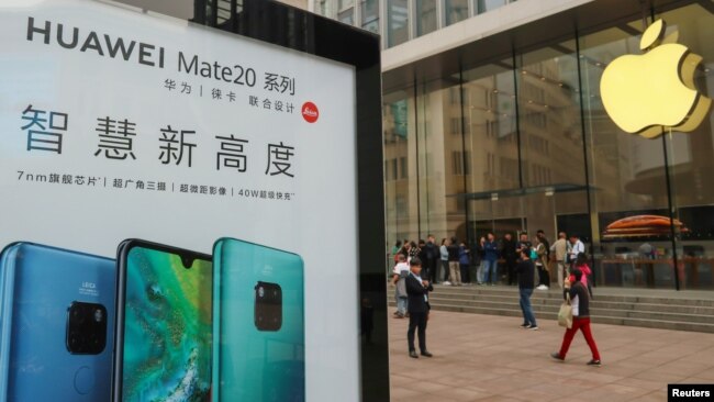在中国上海的Apple商店外面,顾客排队购买新的iPhone XR手机,附近有华为Mate 20系列产品的广告。(2018年10月26日)