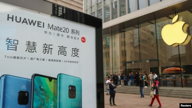 2018年10月26日在中国上海的Apple商店外面,顾客排队购买新的iPhone XR手机,附近有华为Mate 20系列产品的广告。