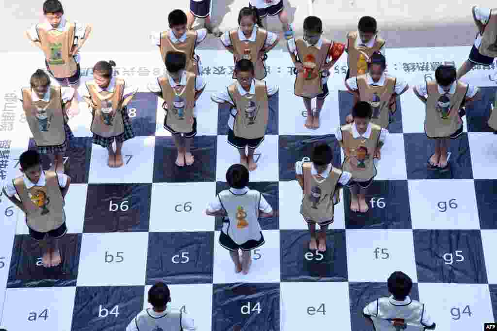 Children play chess on a giant chess board at a primary school in Handan in China&#39;s northern Hebei province. The &quot;live&quot; chess game was played by 32 students to promote chess at the school.