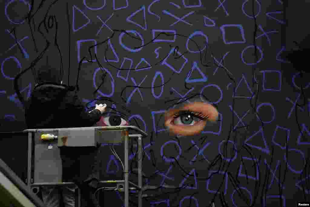 یک نقاش گرافیتی در ایرلند شمالی مشغول کشیدن یک نقاشی دیواری با اسپری، الهام گرفته از برنامه تلویزیونی &laquo;دختران دِری&raquo;، است.