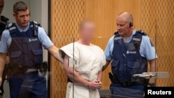 Tersangka penembakan massal Brenton Tarrant (tengah), dikawal polisi saat tampil di pengadilan distrik Christchurch, Selandia Baru, 16 Maret 2019.