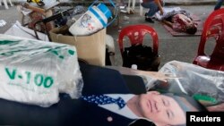 Cut-out image of former Prime Minister Thaksin Shinawatra near body of a man killed near stadium where pro-government Red Shirts gathered, Bangkok, Dec. 1, 2013.