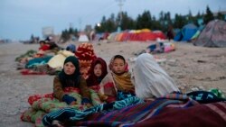 Afghan children are covered with a blanket as their families camp outside the Directorate of Disaster, in Herat, Afghanistan, Nov. 29, 2021.