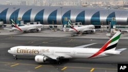 FILE- In this March 22, 2017, photo, an Emirates plane taxis to a gate at Dubai International Airport at Dubai International Airport in Dubai, United Arab Emirates. The Middle East's biggest airline had reduced flights to the United States because of a drop in demand caused by tougher U.S. security measures. 