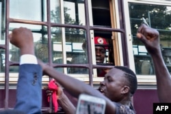 Supporters gather in solidarity with opposition figurehead Robert Kyagulanyi, aka Bobi Wine, gesturing inside the prison bus leading him to Luzira maximum prison in Kampala, April 29, 2019.