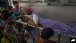 Relatives carry Kashmiri boy boy Tahir Khursheed, wounded in a grenade blast, on a stretcher inside a hospital in Srinagar, Indian controlled Kashmir, July, 11, 2018.