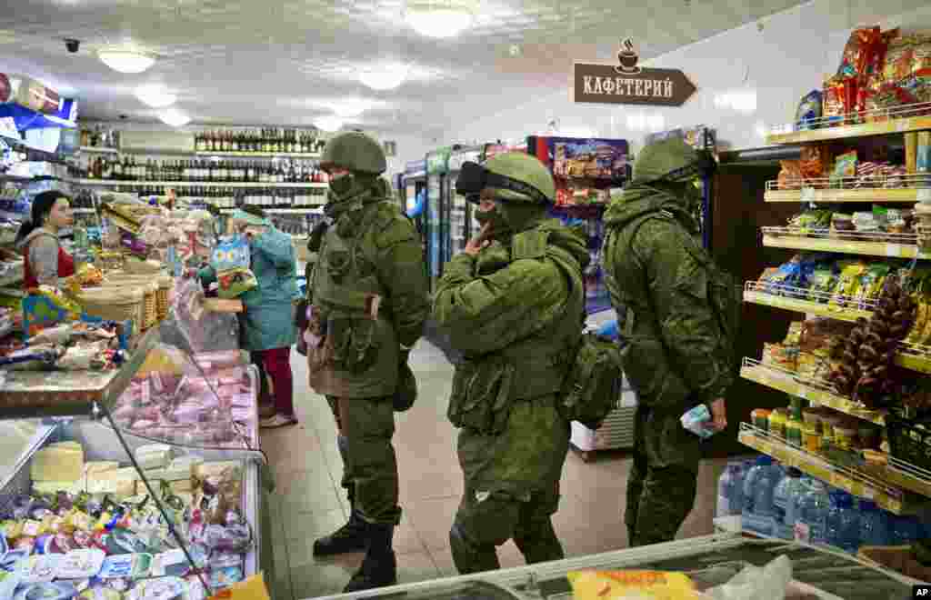 Masked gunmen browse in a shop in Perevalne, Ukraine, March 16, 2014. 