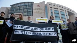Human rights activists stage a protest outside a court in Istanbul, Turkey, Jan. 31, 2018, where a trial of eleven human rights activists, accused of belonging to and aiding terror groups, is ongoing.