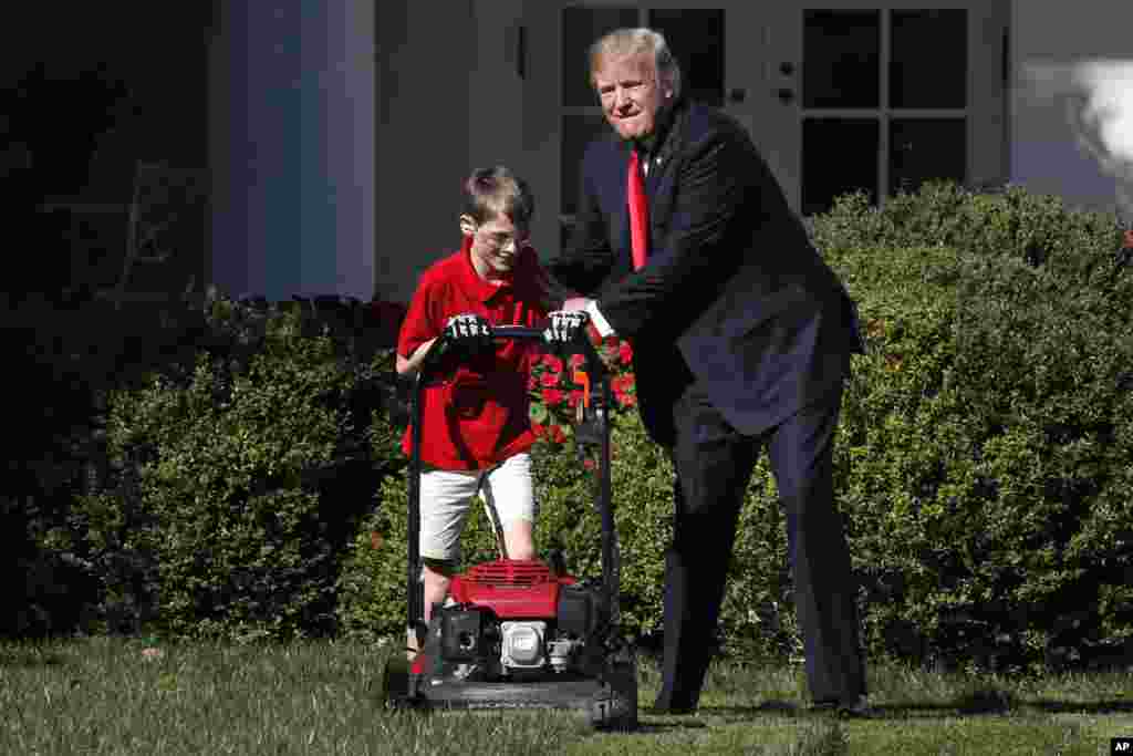 Frank Giaccio, 11, of Falls Church, Va., left, is encouraged by President Donald Trump, Friday, Sept. 15, 2017, while he mowed the lawn in the Rose Garden at the White House in Washington.