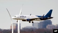 FILE - A JetBlue passenger plane passes the Air Force Memorial as it prepares to land at Reagan Washington National Airport in Arlington, Virginia, across the Potomac River from Washington, D.C., Jan. 19, 2022.