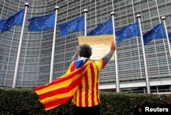 Catalan Raimon Castellvi wears a flag with an Estelada (Catalan separatist flag) as he protests outside the European Commission in Brussels after Sunday's independence referendum in Catalonia, Belgium, Oct. 2, 2017.