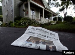 A morning edition of the Washington Post lies in a driveway after delivery in this photo illustration taken in Silver Spring, Maryland, August 6, 2013.