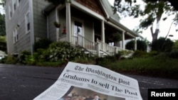 A morning edition of the Washington Post lies in a driveway after delivery in this photo illustration taken in Silver Spring, Maryland, August 6, 2013.