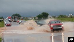 Vehicles drive through floodwater on US Highway 66 following heavy rains, May 21, 2019, in El Reno, Okla.