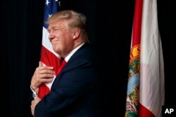 Donald Trump hugs an American flag at a rally.
