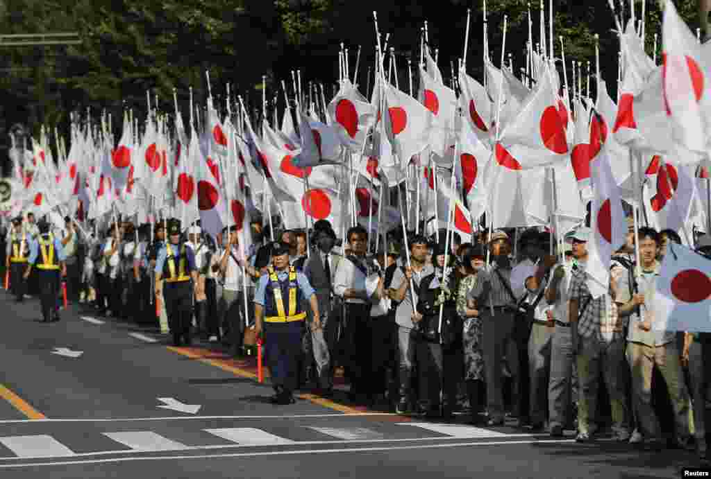 Members of the nationalist movement "Ganbare Nippon" participate in a march with Japanese national flags while paying tribute to the war dead near Yasukuni Shrine in Tokyo, August 15, 2013.