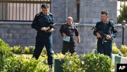 FILE - Police officers patrol Iran's parliament building after an assault by several attackers that was claimed by the Islamic State group, in Tehran, Iran, June 7, 2017. Gunmen and suicide bombers attacked Iran’s parliament and the shrine of its revolutionary founder.