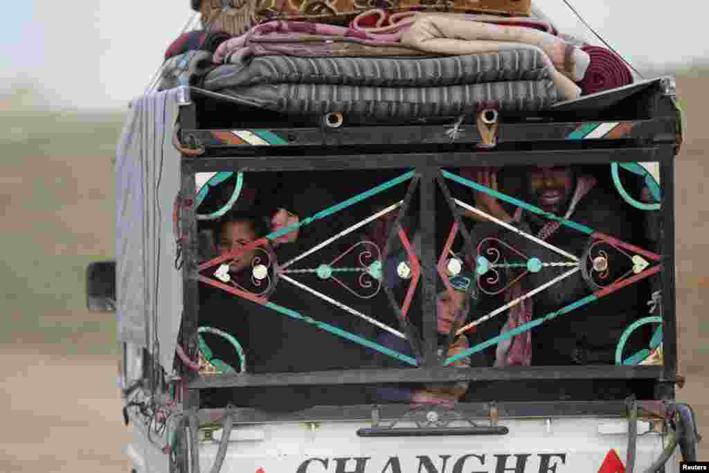 People ride in a vehicle stacked with their belongings after fleeing clashes in the northern Syrian town of al-Bab.