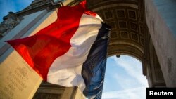 FILE - The French flag flies under the Arc de Triomphe during a ceremony to commemorate the end of the World War One in Paris, Nov. 11, 2013. 