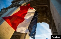 FILE - The French flag flies under the Arc de Triomphe during a ceremony to commemorate the end of the World War I in Paris, Nov. 11, 2013.