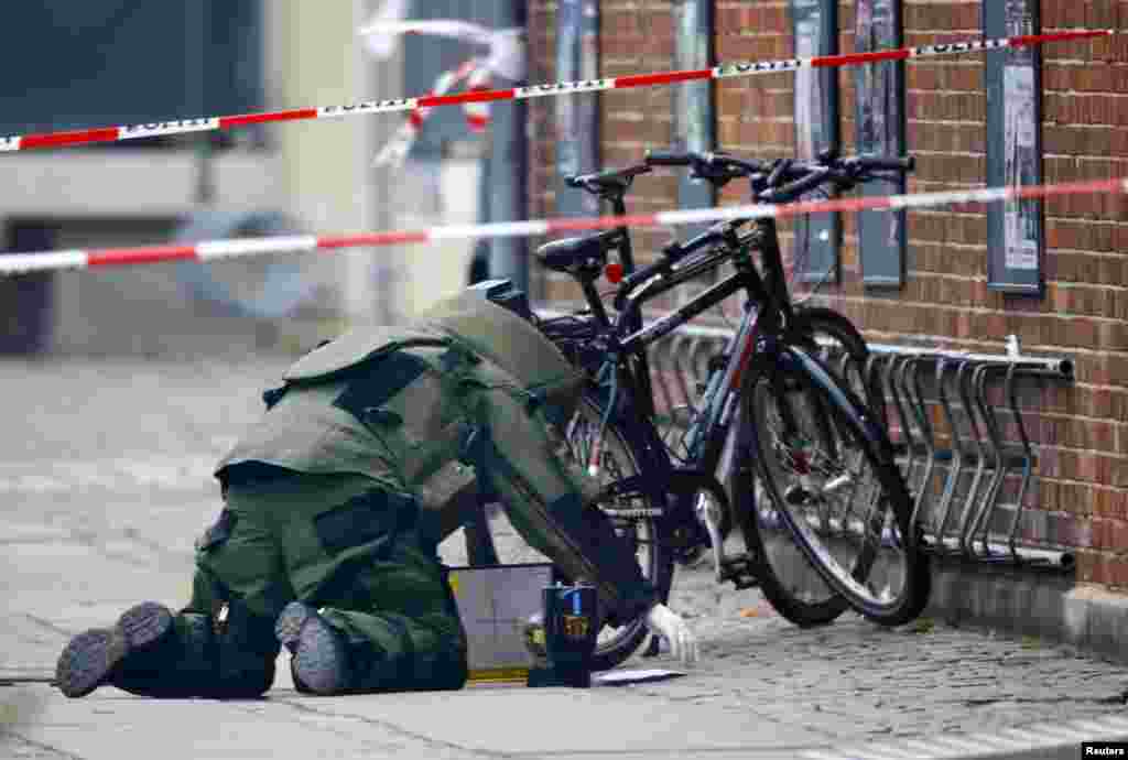 A bomb disposal expert investigates an unattended package in front of a cafe in Oesterbro, Copenhagen, Denmark. Police found no explosives in the package that was left in front of the cafe where the deadly shooting attack took place on Feb. 14, 2015, police said in a twitter message.