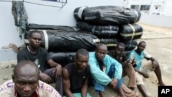 Ghanaian drug-runners sitting in front of bales of cannabis seized by the anti-drug section of the Ivorian gendarmerie in Abidjan (File Photo)