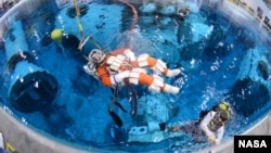 Steve Bowen is lowered into the Neutral Buoyancy Laboratory at Johnson Space Center to test spacewalk suits and tools for a mission to an asteroid.