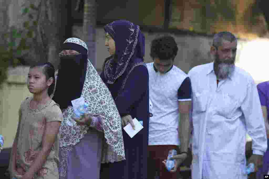Muslims stand in a line to cast their vote outside of a polling station in Mandalay, Nov. 8, 2015.