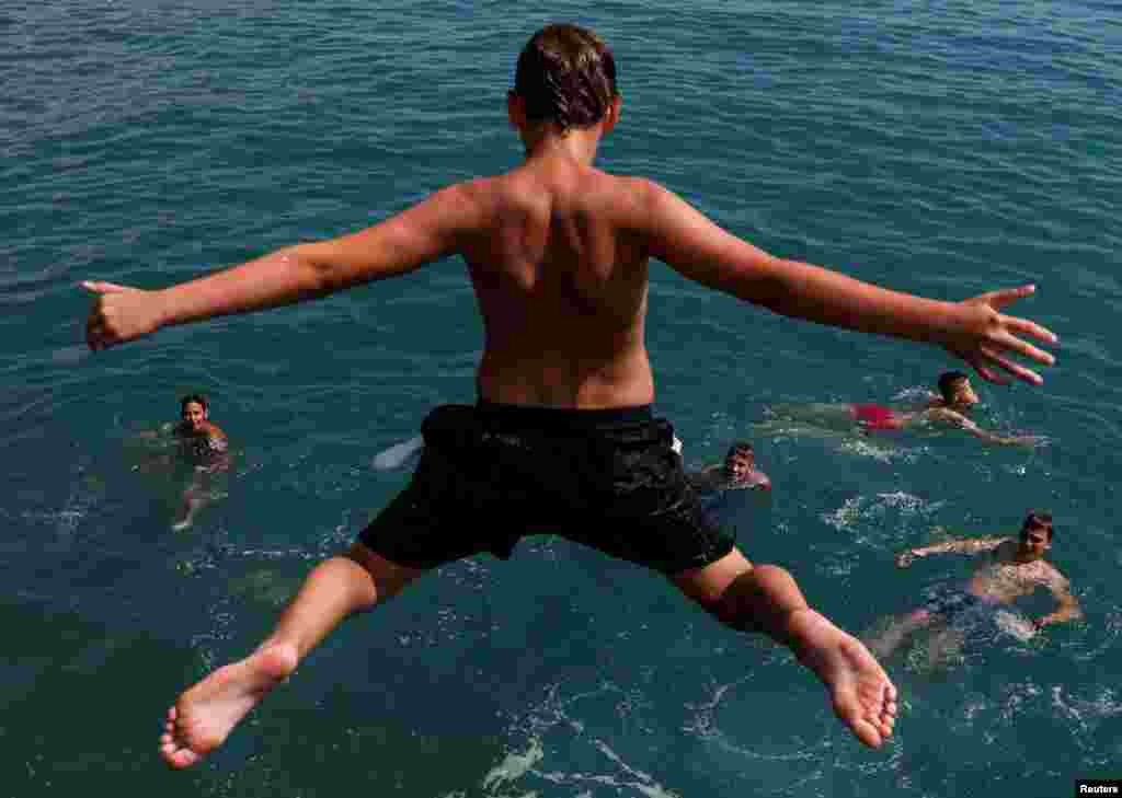 A boy jumps into the Black Sea from a pier in central Sochi, Russia.