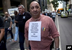 A police officer carries a sign that states in Portuguese that unpaid police can't risk their lives in the line of duty, in Rio de Janeiro, Brazil, June 27, 2016.