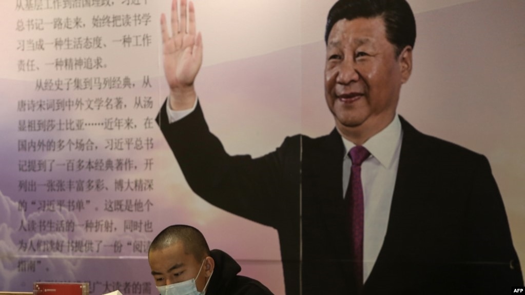 中国辽宁省沈阳市的一家书店里一名戴着口罩的读者坐在中国国家领导人习近平的大幅画像前。（2020年4月23日）(photo:VOA)