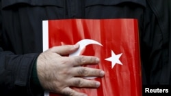 FILE - A supporter of Gulen movement holds a Turkey's national flag during a protest outside the Kanalturk and Bugun TV building in Istanbul, Turkey, Oct. 28, 2015. 