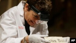 Pam Hatchfield, head of objects conservation at the Museum of Fine Arts in Boston, removes a folded 19th-century newspaper from a time capsule at the museum, Jan. 6, 2015.