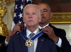 In this Jan. 12, 2017, file photo President Barack Obama presents Vice President Joe Biden with the Presidential Medal of Freedom during a ceremony in the State Dining Room of the White House in Washington.