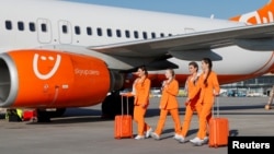 Flight attendants of SkyUp Airlines walk along a tarmac during the presentation of a new uniform at the Boryspil International Airport outside Kyiv, Ukraine September 30, 2021. The uniform includes loose clothing and comfortable shoe. (REUTERS/Gleb Garanich)