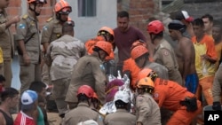Para petugas mengevakuasi jenazah dari bawah puing setelah longsor di kawasan kumuh di Niteroi, Brazil, 10 November 2018.