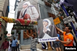 FILE - A man holds a poster of Mother Teresa outside the Missionaries of Charity building in Kolkata India, Sept. 4, 2016. A Nobel peace laureate and saint, even she has her critics.