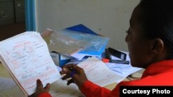 Benedetta Kamene, Volunteer Children's Officer, reviews a stack of newly-issued birth certificates at the Kimadzo community-based organization, Kwale, Kenya, July 25, 2012. (VOA/Jill Craig)