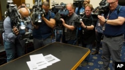 Photojournalists photograph four pages of the Mueller Report laid on the witness table in the House Intelligence Committee hearing room on Capitol Hill, April 18, 2019. (AP Photo/Cliff Owen)