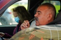 Jose Alfrtedo De la Cruz and his wife, Rogelia, self-test for COVID-19 at a drive-through testing center in Whittier, Calif., Jan. 25, 2022.
