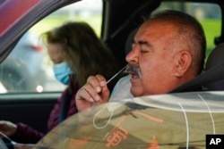 Jose Alfrtedo De la Cruz and his wife, Rogelia, self-test for COVID-19 at a drive-through testing center in Whittier, Calif., Jan. 25, 2022.