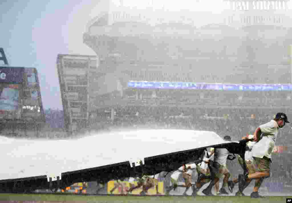 지난 2일(현지시간) 뉴욕 양키스타디움에서 미 프로야구(MLB) 뉴욕 양키스와 디트로이트 타이거스 경기 도중 비가 쏟아지자, 구장 관계자들이 지면에 방수포를 덮고 있다.