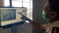 Petugas Kantor Kesehatan Pelabuhan Kelas 1 Surabaya menunjukkan tampilan monitor dan suhu tubuh penumpang yang melewati pintu kedatangan luar negeri (foto Petrus Riski-VOA).