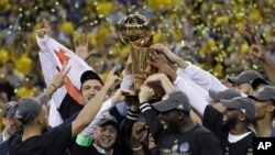 Golden State Warriors players, coaches and owners hold up the Larry O'Brien NBA Championship Trophy after Game 5 of basketball's NBA Finals between the Warriors and the Cleveland Cavaliers in Oakland, Calif., June 12, 2017.
