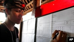 An electoral worker checks a vote for presidential candidate Joko "Jokowi" Widodo during the vote counting at a polling station in Bali, Indonesia, April 17, 2019.