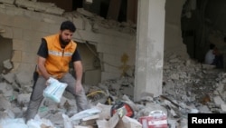 A Red Crescent aid worker inspects scattered medical supplies after an airstrike on a medical depot in the rebel-held Tariq al-Bab neighborhood of Aleppo, April 30, 2016.